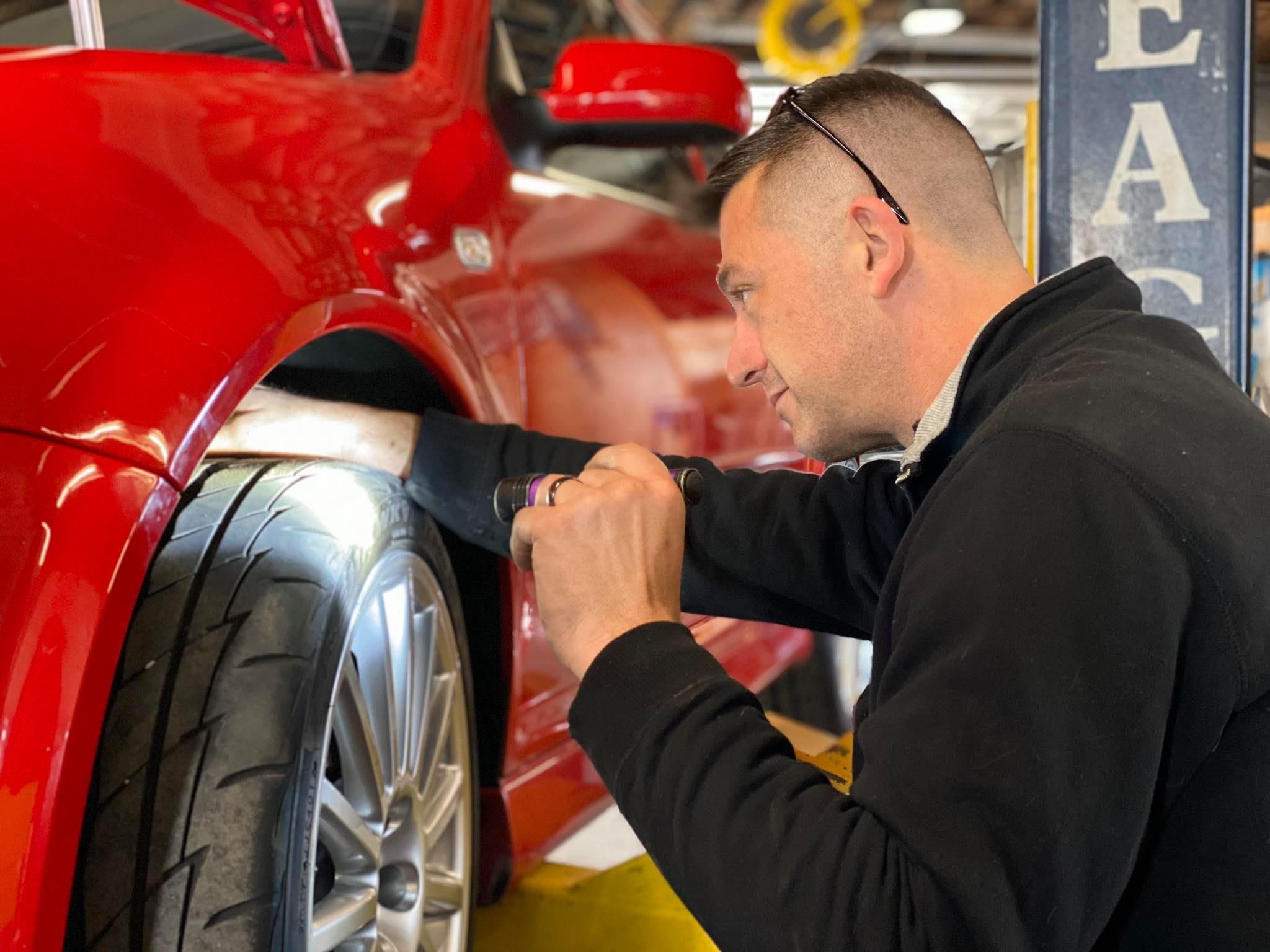 Technician inspecting wheel well and brakes on a European vehicle