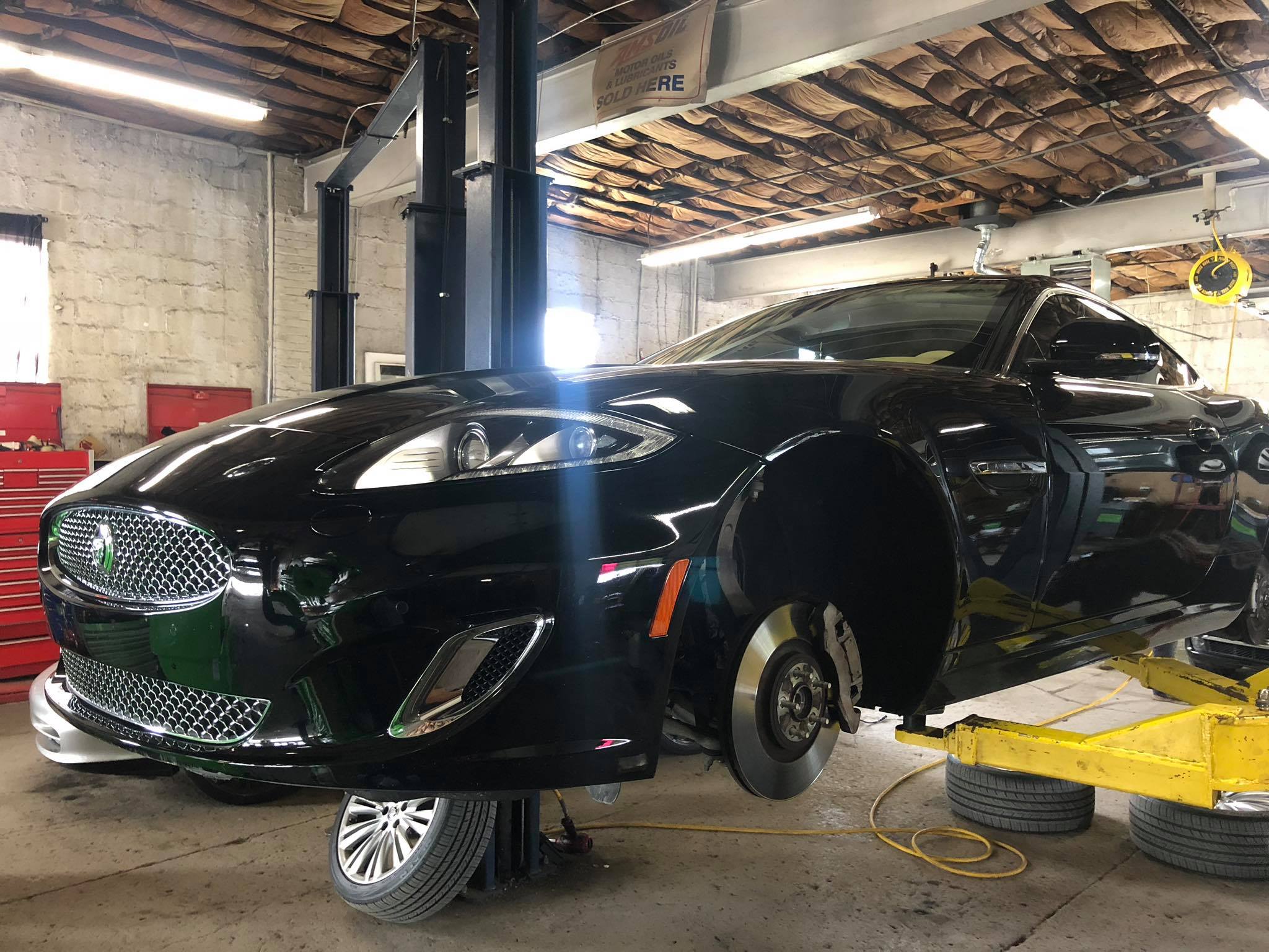 Maserati raised on lift with wheels removed for brake service at European auto repair shop
