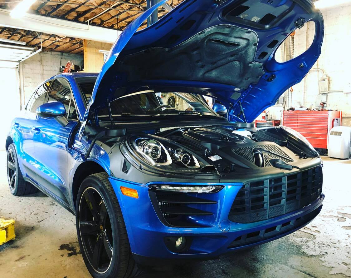Beautiful blue Porsche arriving at European auto repair shop for routine maintenance